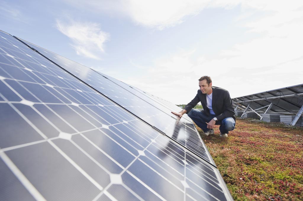 homme accroupi regarde des panneaux solaires