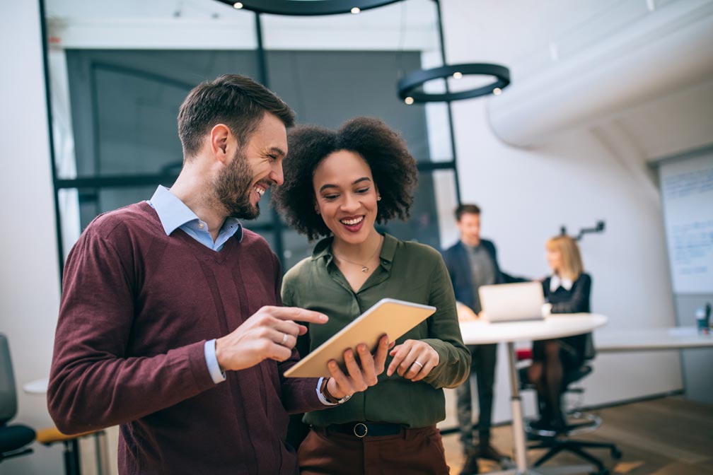 homme et femme au travail discutent avec le sourire